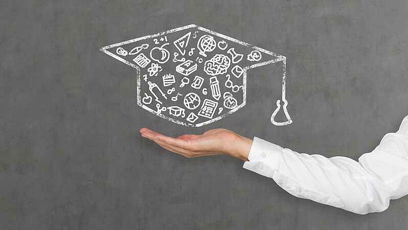 A chalk drawing of a doctoral hat on a blackboard, with various scientific icons inside it; below it, an arm appears in the picture, its hand seemingly holding the hat.