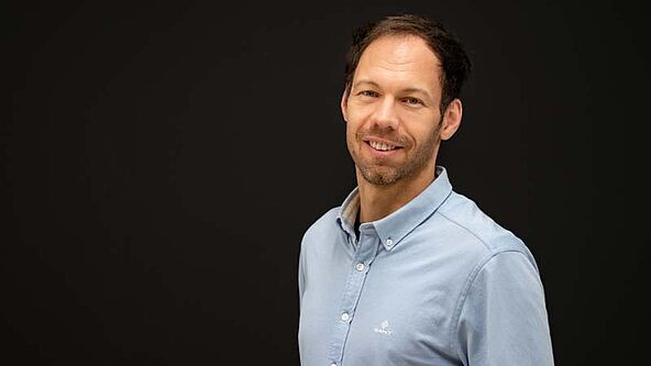 Portraitfoto einer Person vor einem fast-schwarzen Hintergrund