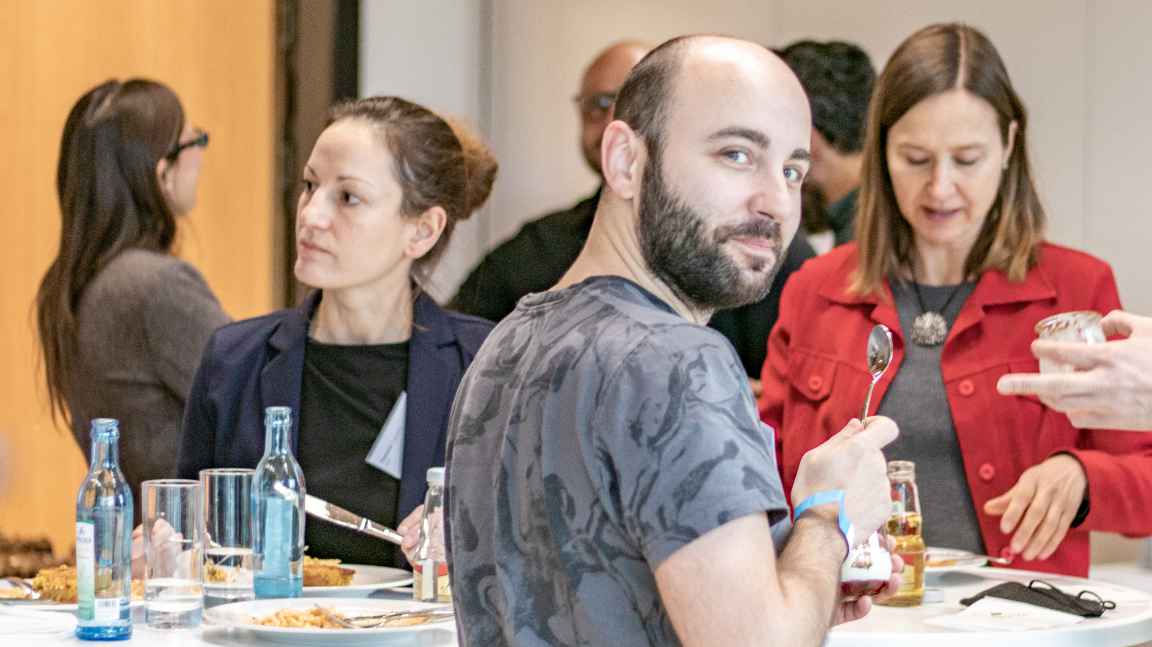 People standing around a bar table having lunch